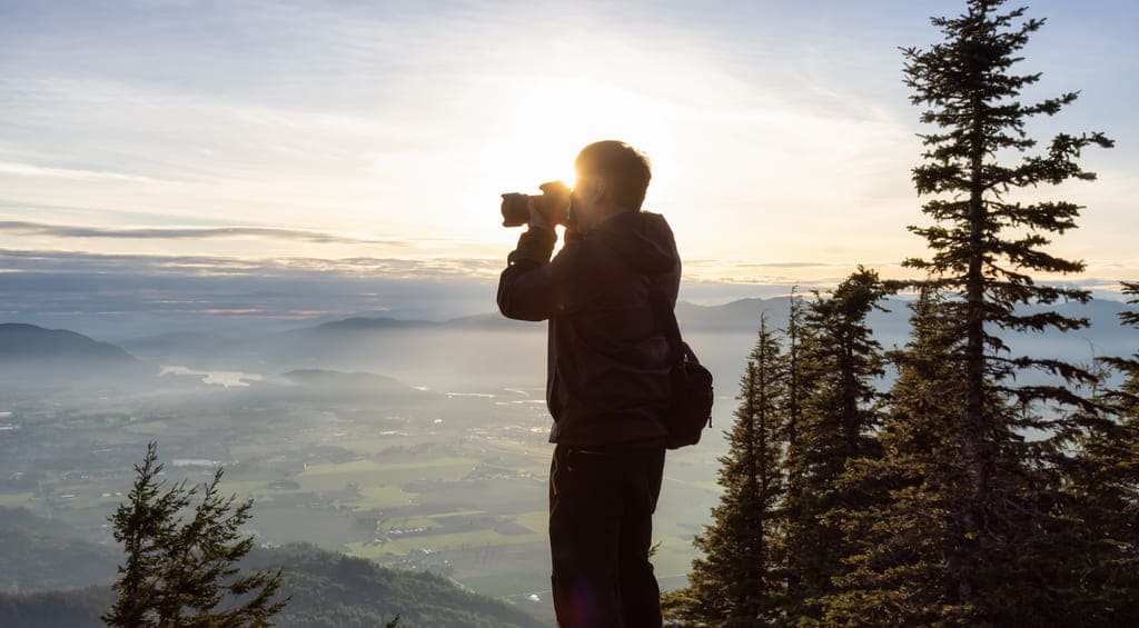 Homem fotografando uma paisagem na natureza.