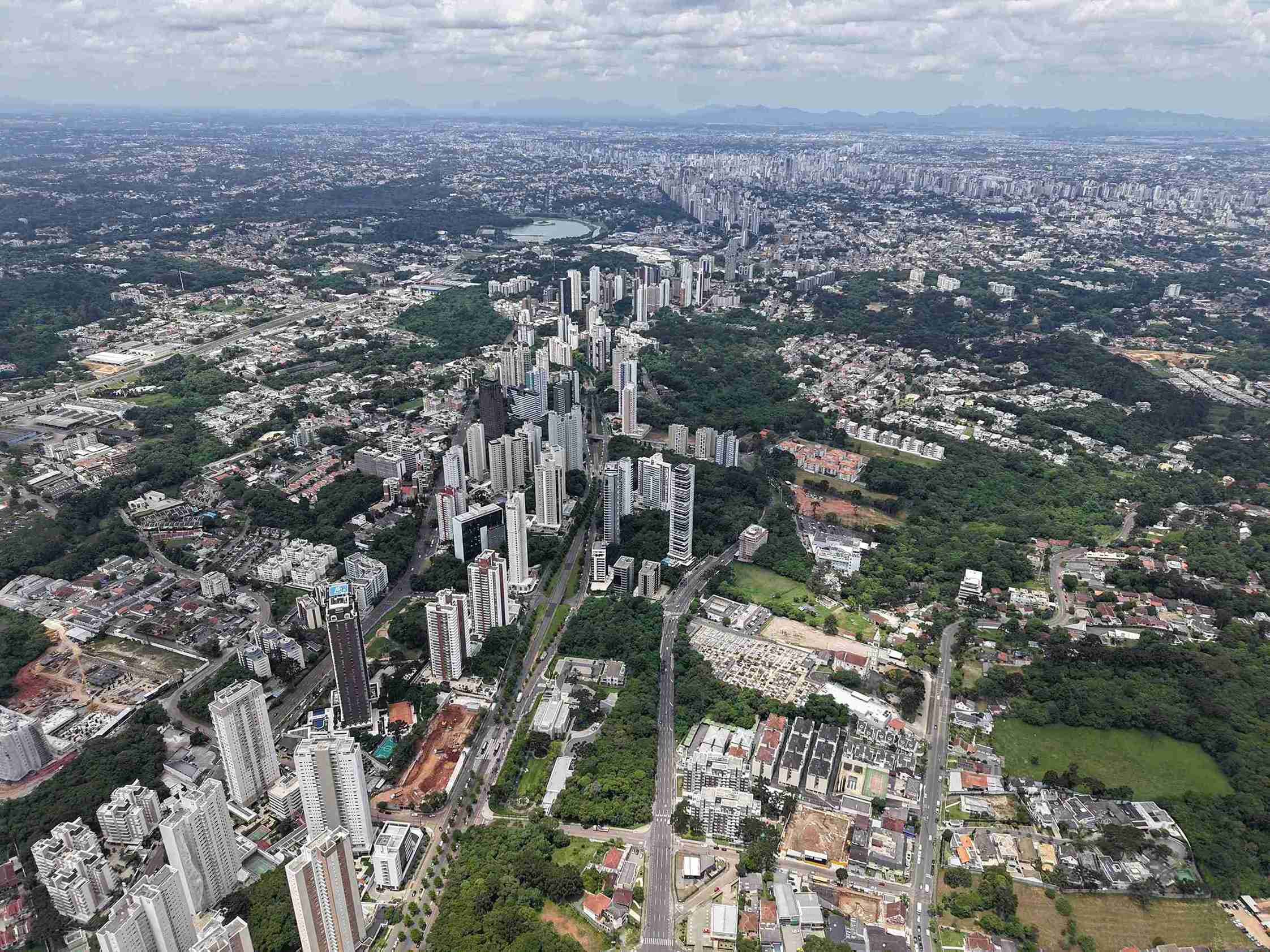 Imagem aérea do bairro Ecoville em Curitiba, com prédios altos cercados por áreas verdes, ideal para quem busca qualidade de vida ao morar em Curitiba.