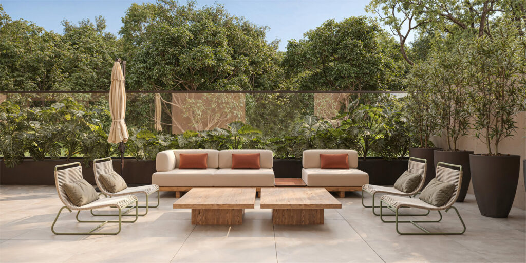 Espaço externo de convivência com sofás e poltronas acolchoadas em meio à vegetação, representando a arquitetura do bem-estar como refúgio emocional no lar.